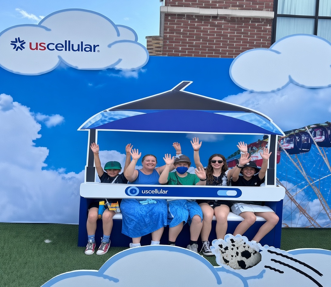 Family in a UScellular photo-op set waving from a branded bench